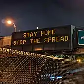 Variable-message sign reading "STAY HOME, STOP THE SPREAD"