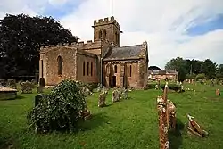 Yellow stone building with square tower set in graveyard.