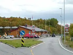 Storskog border station from the Norwegian side. Border posts are visible between the building and the dark van.
A Russian watch tower rises on the hill in the background.