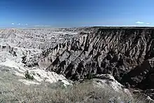 Rocky sand-color mesa table surrounded by many steep erosion gullied