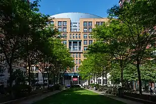 View of Stuyvesant High School's facade from about a quarter-mile away. Most of the facade is orange brick, but the three-story entranceway at the center of the image is made of metal.