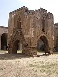 A cube-shaped stone structure built above the ground on four arched pillars