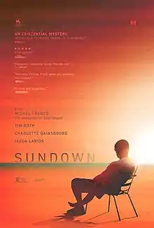 A man sitting in a chair watches a sunset.