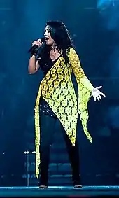 Sunidhi Chauhan performing on stage wearing a black and yellow dress