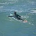 A surfer paddling.