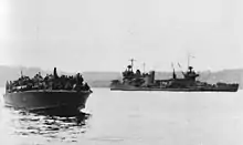 New Orleans seen after the Battle of Tassafaronga near Tulagi on 1 December 1942. The PT boat in the foreground is carrying survivors from Northampton.