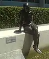 Susanne (2005), life-sized bronze nude, sits on a wall beside a reflecting pond, BBP.