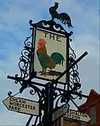 A finger post in Sutton town centre, London, incorporating the sign of the former Cock inn