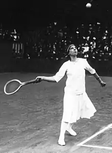 Lenglen about to hit a forehand at the baseline with the ball above head-height