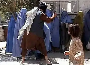 A Taliban religious policeman beating a woman because she removed her burqa in public.