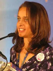 A three quarter profile shot of the author, with shoulder length brown hair and a purple and pink shirt.