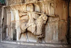 Relief in a wall, looking at the right-hand size of an armoured hose with a rider who carries a spear