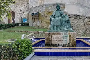 Statue of a sitting man outside a city wall