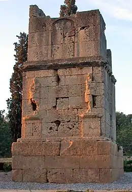 Photo of an ancient crumbling monument that includes two standing figures.