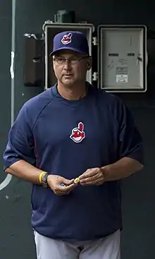 A man in a navy shirt and cap and gray pants