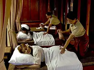 Two masseurs massaging their clients using stretching.