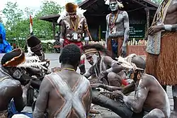 Asmat people performing traditional wood carving.