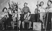 Seven of the eight Bushwhackers in 1955, from the rear cover of their 1957 "Australian Bush Songs" EP. L-R: Chris Kempster, guitar; John Meredith, accordion; Alex Hood, bones; Harry Kay, harmonica; Alan Scott, tin whistle; John Barrie, tea chest bass; Cec Grivas (in place of Brian Loughlin), lagerphone. Brian Loughlin (obscured) was seated behind Kempster; his left leg (with carpet slipper) is just visible in this photograph.