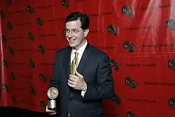 Colbert holding a Peabody Award and giving a thumbs up