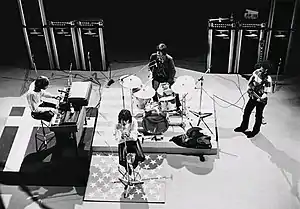 A black and white image of four white men performing onstage.