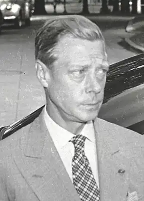  A middle-aged man with fair hair, wearing a light-coloured jacket and cross-striped tie, looks to the right with a furrowed brow and pursed lips.