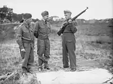 Local Defence Volunteers receiving rifle instruction. Two on left wear Overalls, Denim; the sergeant instructor wears standard battledress.