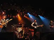 The Killers performing onstage playing and singing into a microphone