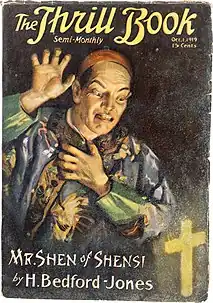 A man in Chinese dress raising a hand threateningly, against a dark background