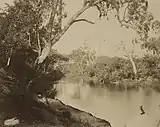 Dirt road in foreground with sailing ships at wharf in background