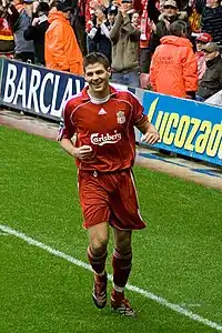 Gerrard smiling as he jogs along the side of a pitch