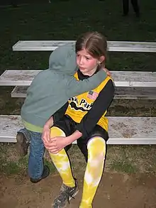 A small child hugs an older, injured child