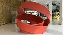 Large red rubber band sculpture, made of steel and installed inside a building lobby