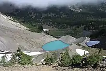 A lake on the slope of Three Fingered Jack can be seen next to the ice of a glacier