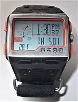 The Timex Expedition WS4 in time display mode. The temperature displays 28.1 degrees Celsius while the sun icon indicates the barometric pressure trend is positive, forecasting improving weather ahead. The digital time is also displayed through an LCD watch with analogue hands located on the upper left corner of the dashboard.