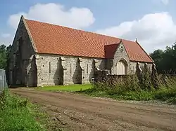 Long stone building with buttressed walls and red tiled roof