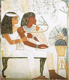 Nakht smelling a lotus while being embraced by his wife, Tawy, while also sitting in front of a set of offerings. Tomb TT52, Thebes, Egypt