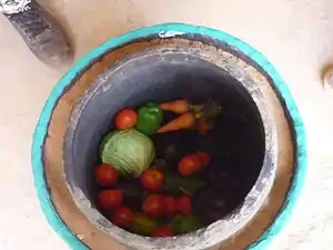 A large clay pot filled with a variety of vegetables including cabbage.