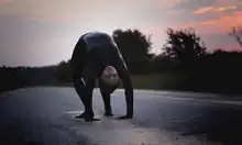 A woman covered in black paint and walking upside-down.