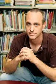 photograph of author seated in front of bookshelves