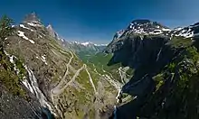 An S-bend road climbing a valley with jagged peaks