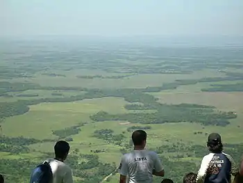 Three people looking out over a green, wooded vista