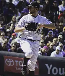 A man in a white baseball uniform and black cap