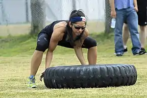 Woman lifting a 200 pound tyre - bent knees essential to avoid back strain.