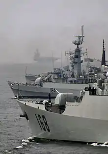 PNS Badr anchored with the Chinese Navy Guangzhou, the American USS Lake Champlain, and USS Theodore Roosevelt (the aircraft carrier in background) during the naval drill, Aman-09, hosted by Pakistan in the Indian Ocean in 2009.
