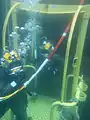 US Navy divers descending to a wreck to recover petroleum from a sunken ship.