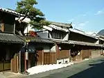 Two storied traditional Japanese houses next to a street.