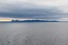 Ugamak Island as seen from the Bering Sea looking east towards Unimak Island. Ugamak is in the foreground and Shishaldin and Isanotski volcanoes on Unimak Island are in the background.