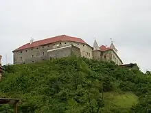 A large stone building with two towers on the top of a hill