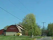 A red and beige barn with the words "Unionville Vineyards" with the intersection of 2 gravel roads in the foreground.