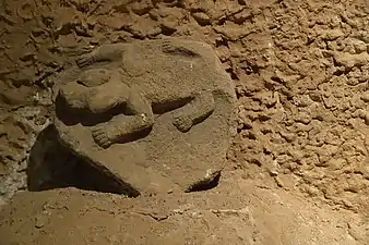 Carved stone with animal (possibly a reptile, felid, or wolverine) in high relief.